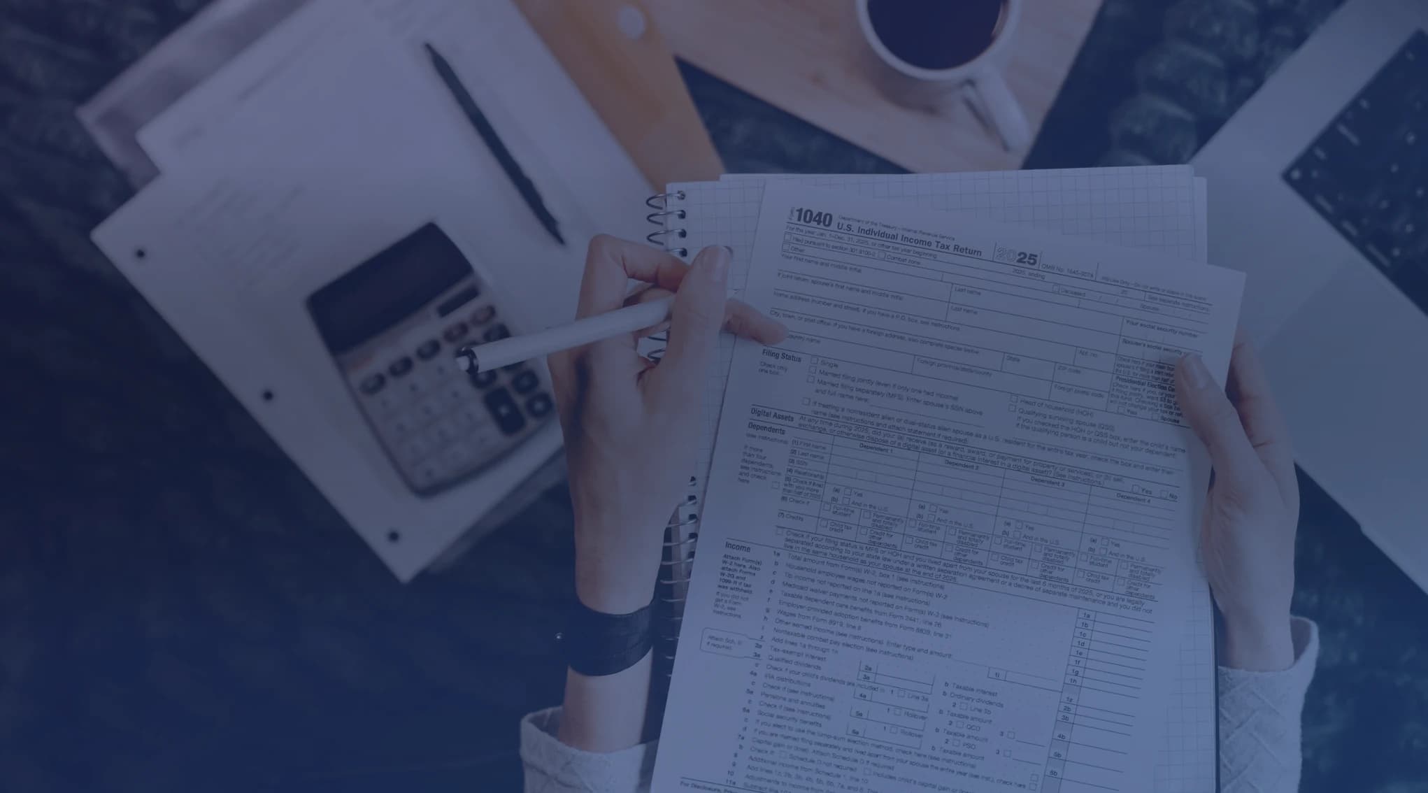 Hands reviewing paperwork with a calculator and a laptop on a desk