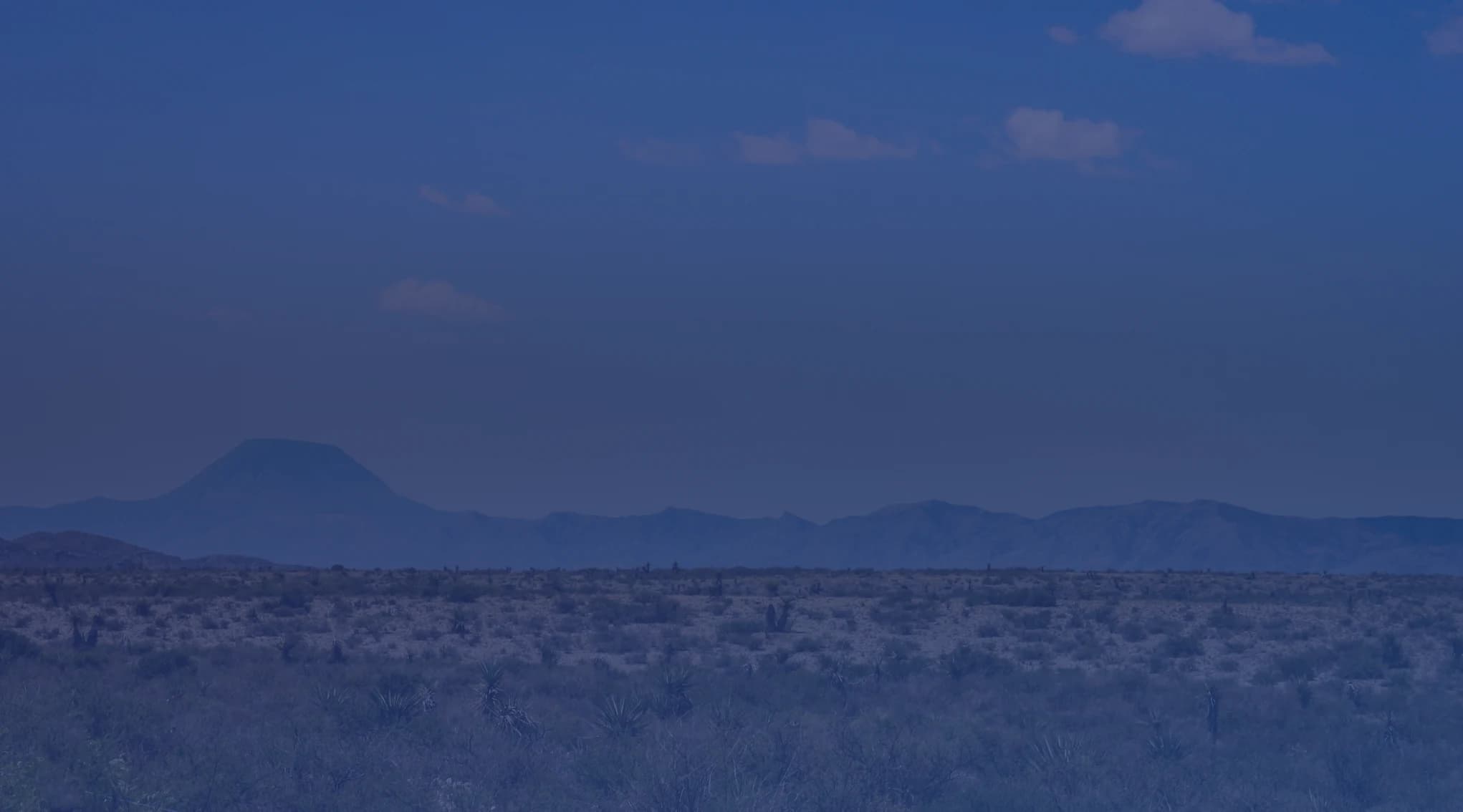 Wide open West Texas grassland and desert landscape under a hazy sky near San Angelo, the Concho Valley region where Goodfellow AFB is located