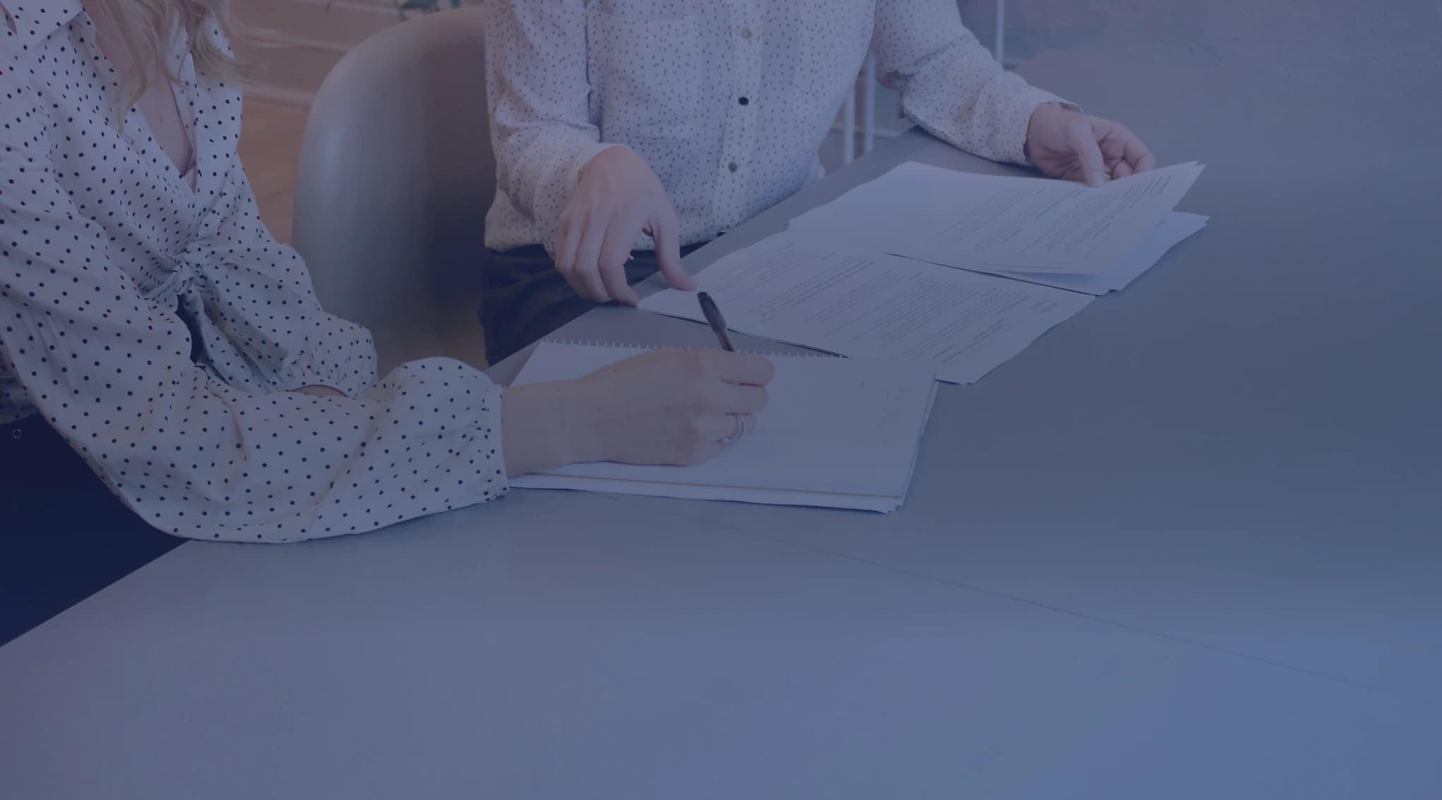 Two people reviewing and signing loan documents together at a desk