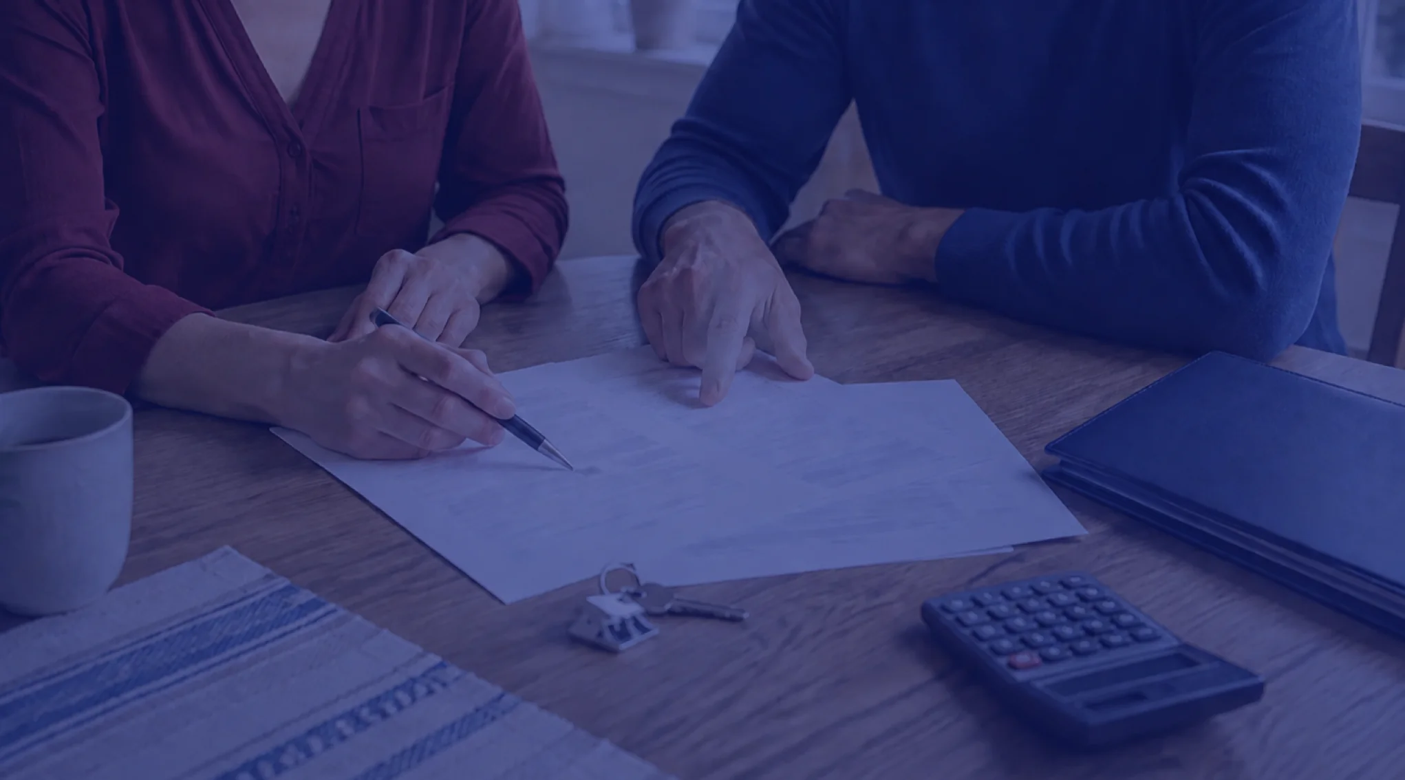 Homeowners reviewing mortgage paperwork, a calculator, and house keys