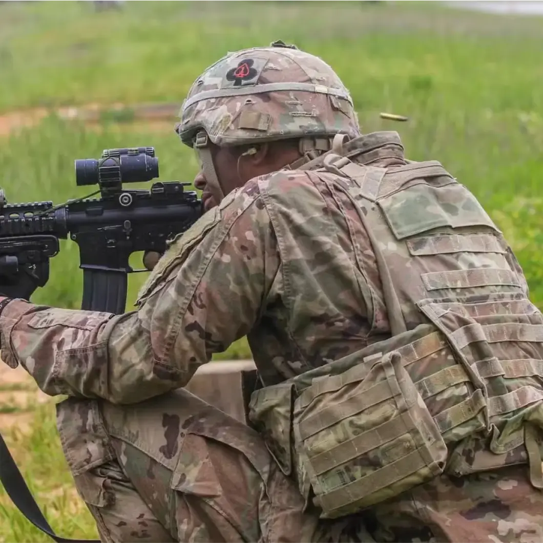 A solider steadies his rifle in the kneeling position.