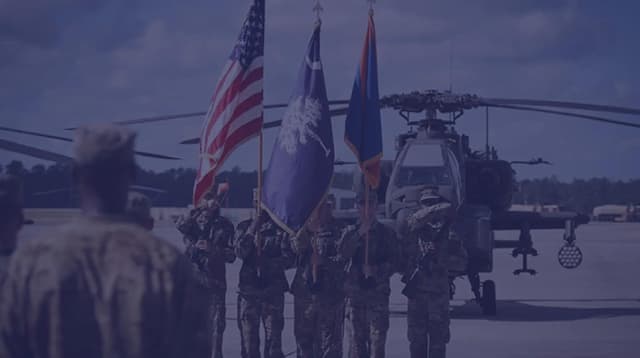 A change of command ceremony in front of AH-64 Apache helicopters.